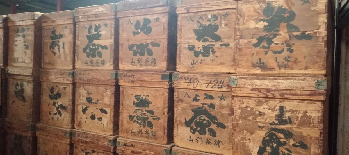 Traditional wooden tea chests stacked inside a cool Yame aging storehouse.