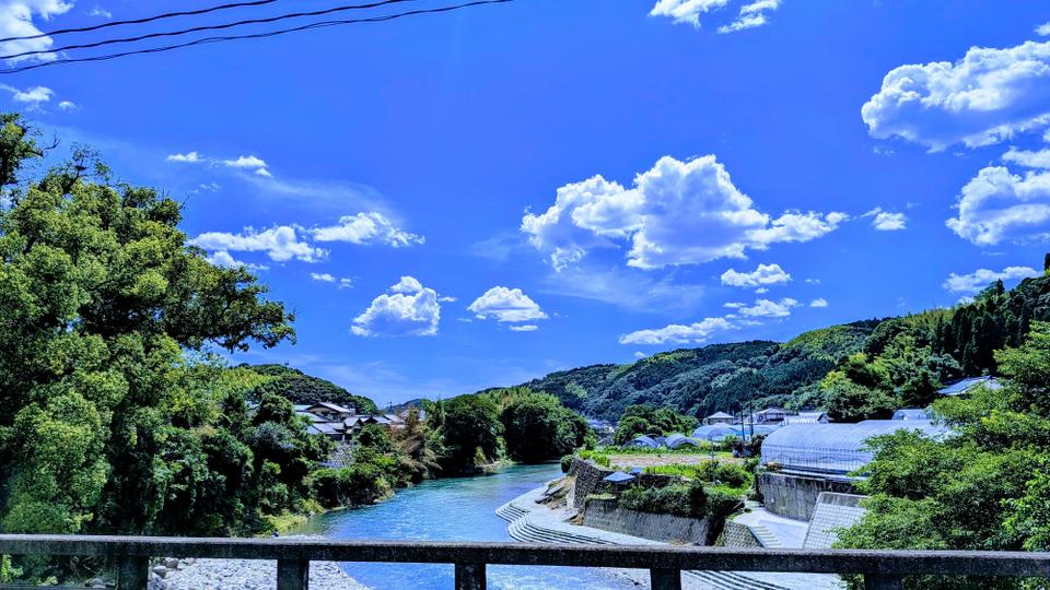 Hoshino River winding through the green mountains of Yame under a bright summer sky.